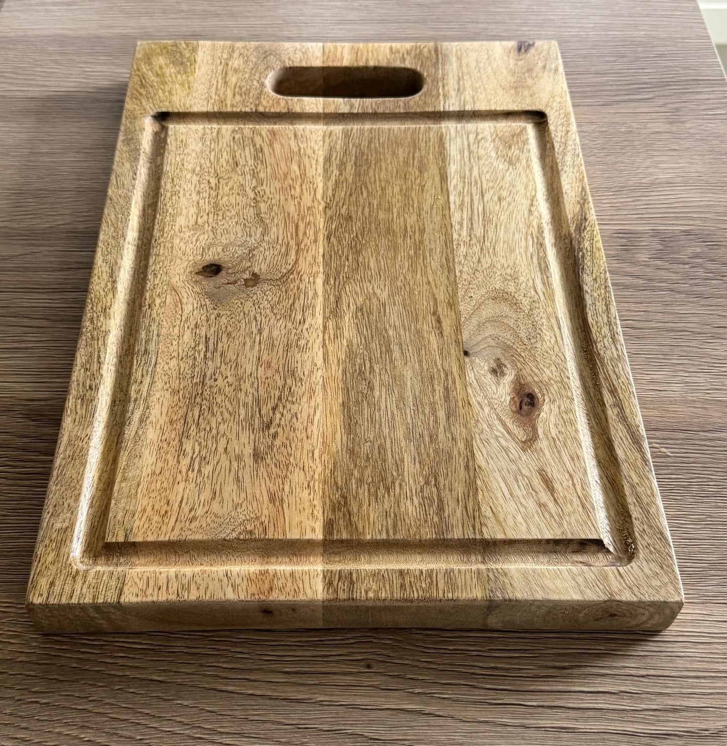 BD-22 Chunky Mango wood carving board with cut out handle on a worktop