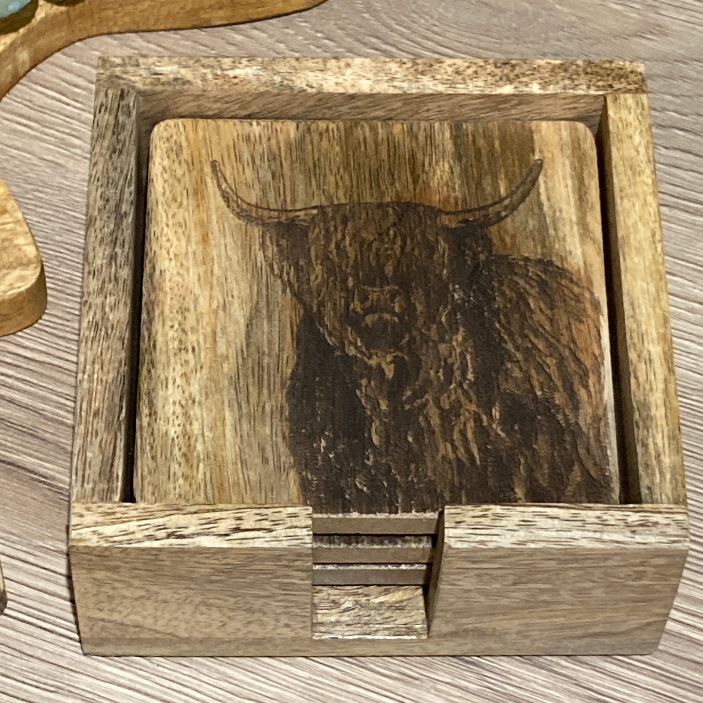 Set of 4 Mango wood square coasters with holder. 10cm square - Etched with Highland cow. Holder on table.
