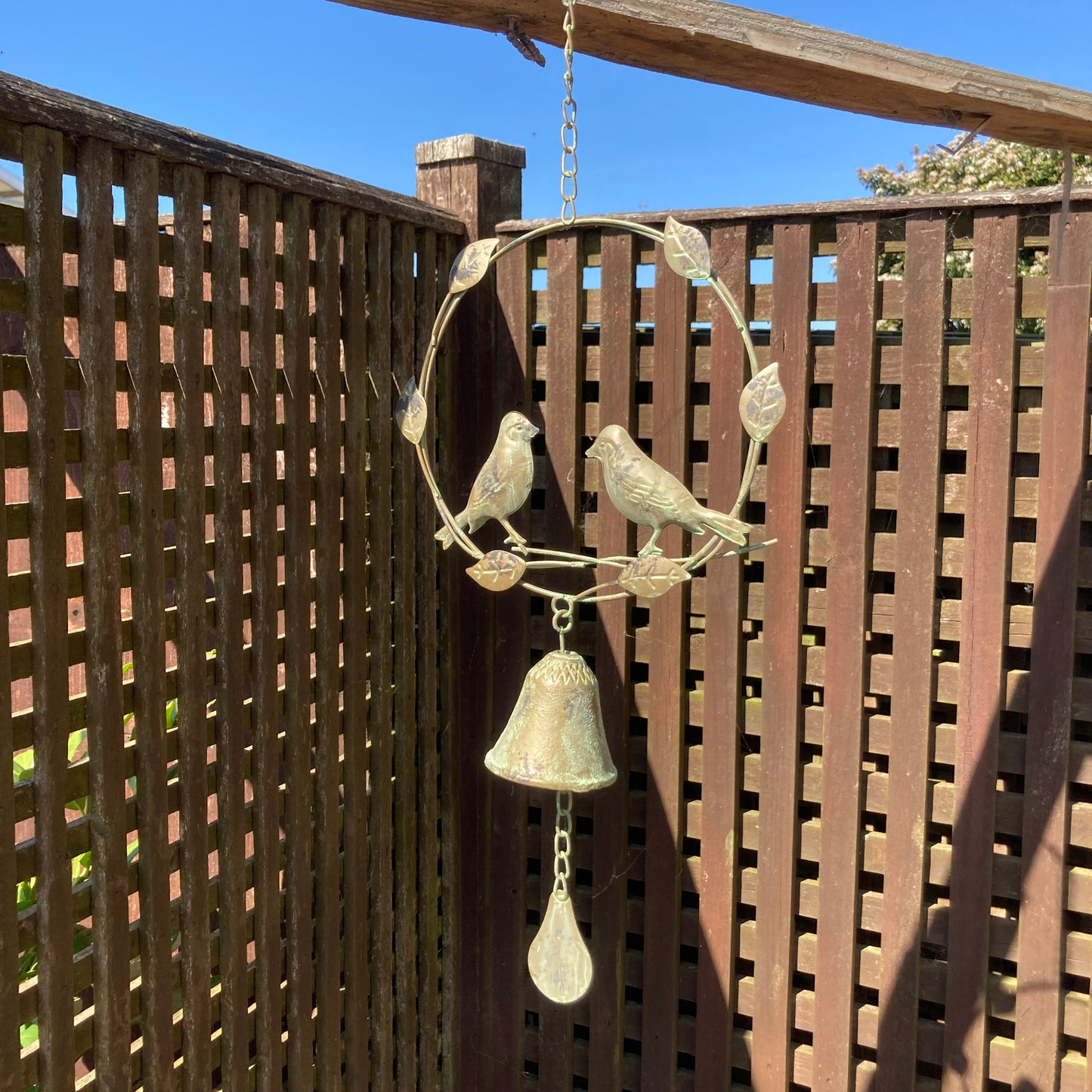 Hanging bird wind chime / bell. Hanging from a wooden structure.