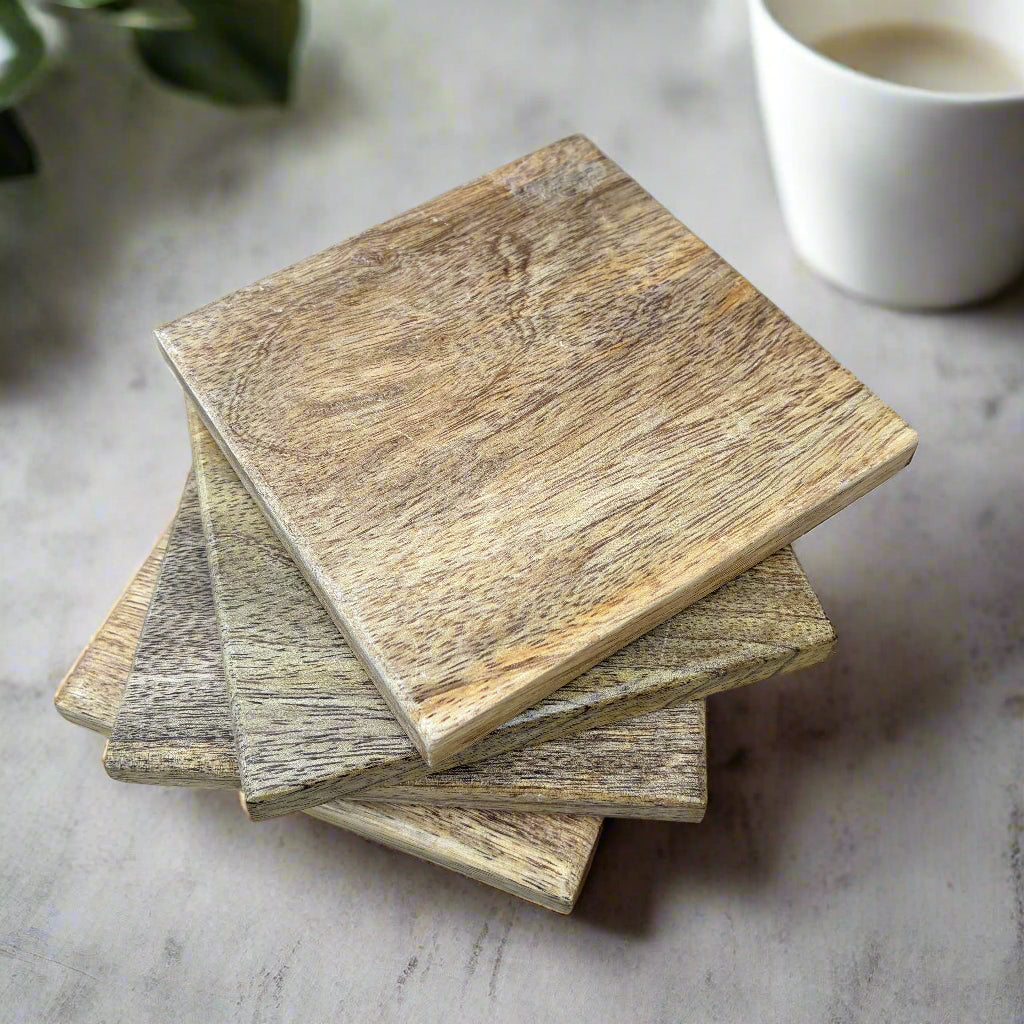 Stack of wooden coasters on a light surface with a cup in the background