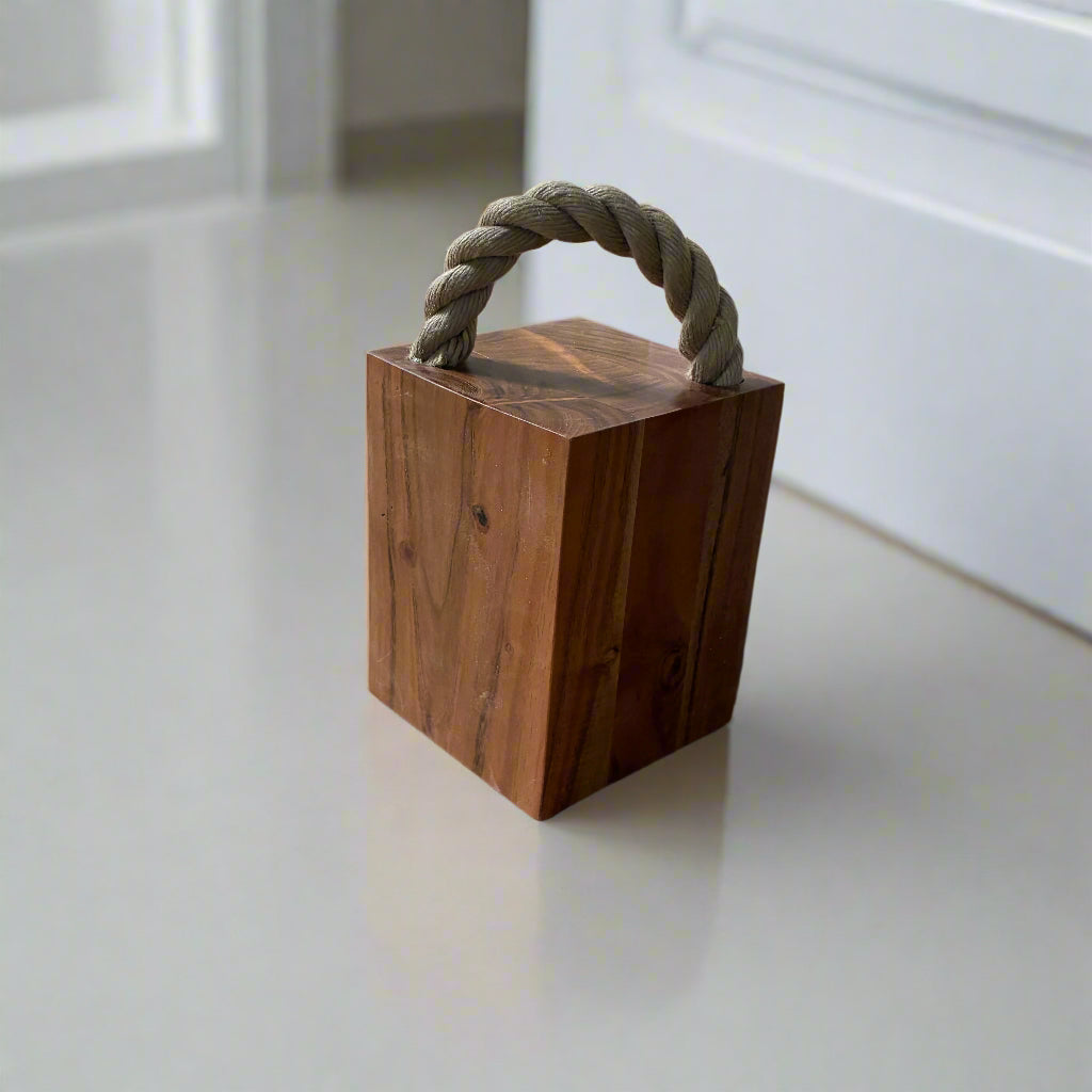 Wooden door stopper with a rope handle on a tiled floor.