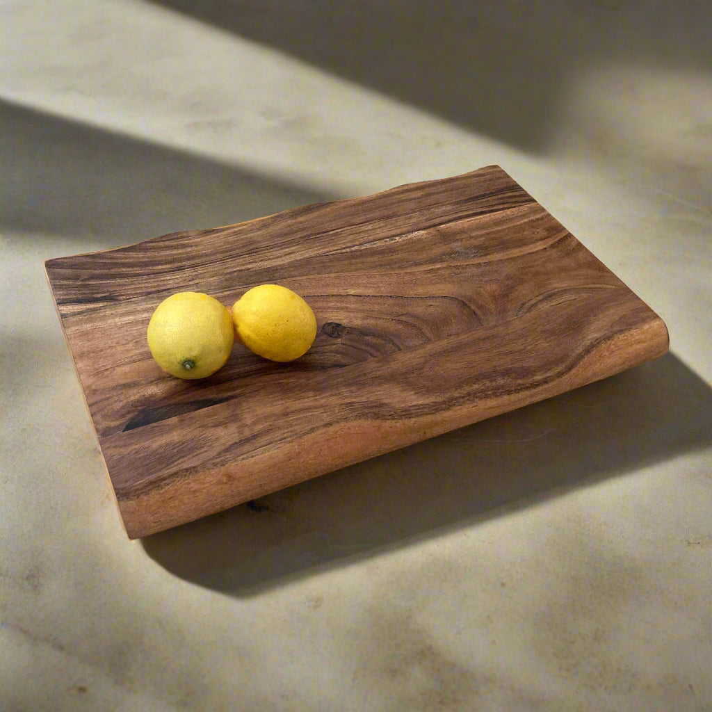 Solid Handmade Acacia Thick Chopping Board with Hand Grooves with lemons at an angel.