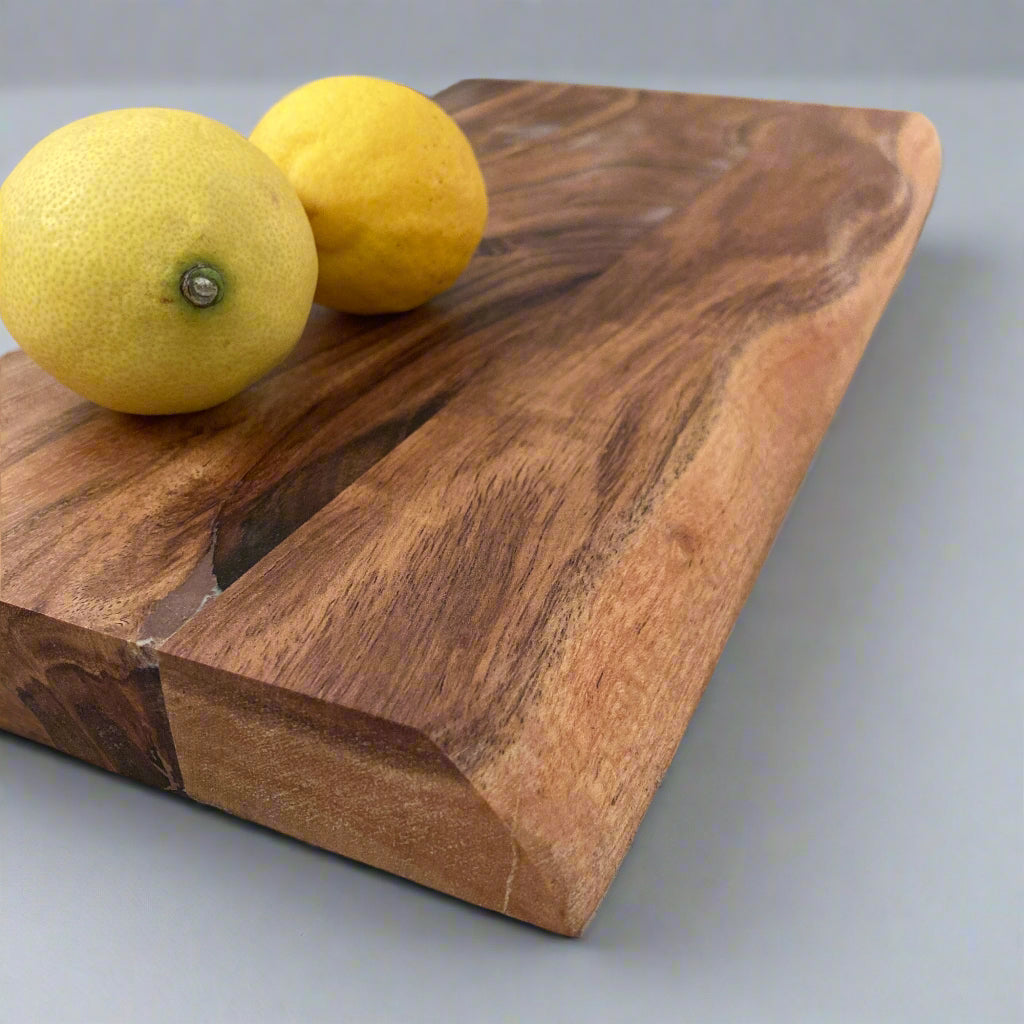 Solid Handmade Acacia Thick Chopping Board with Hand Grooves close up with lemons