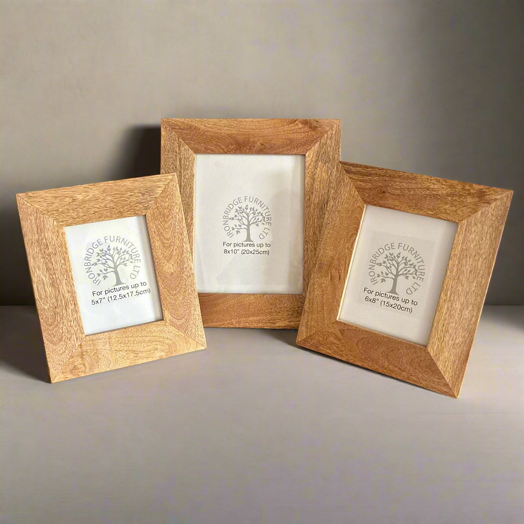 Three wooden picture frames with engraved designs on a neutral background