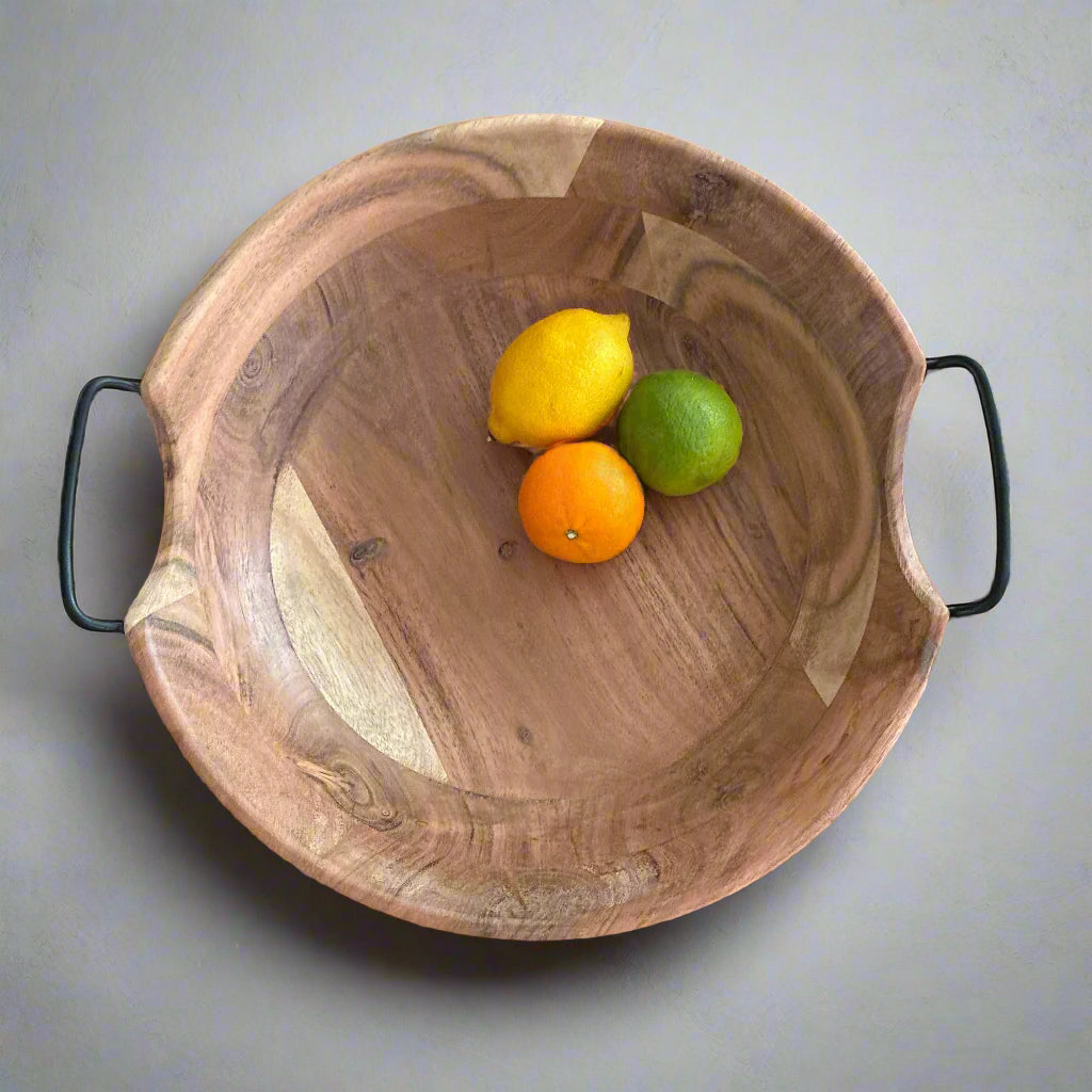 Wooden bowl with lemons, oranges, and a lime on a grey surface