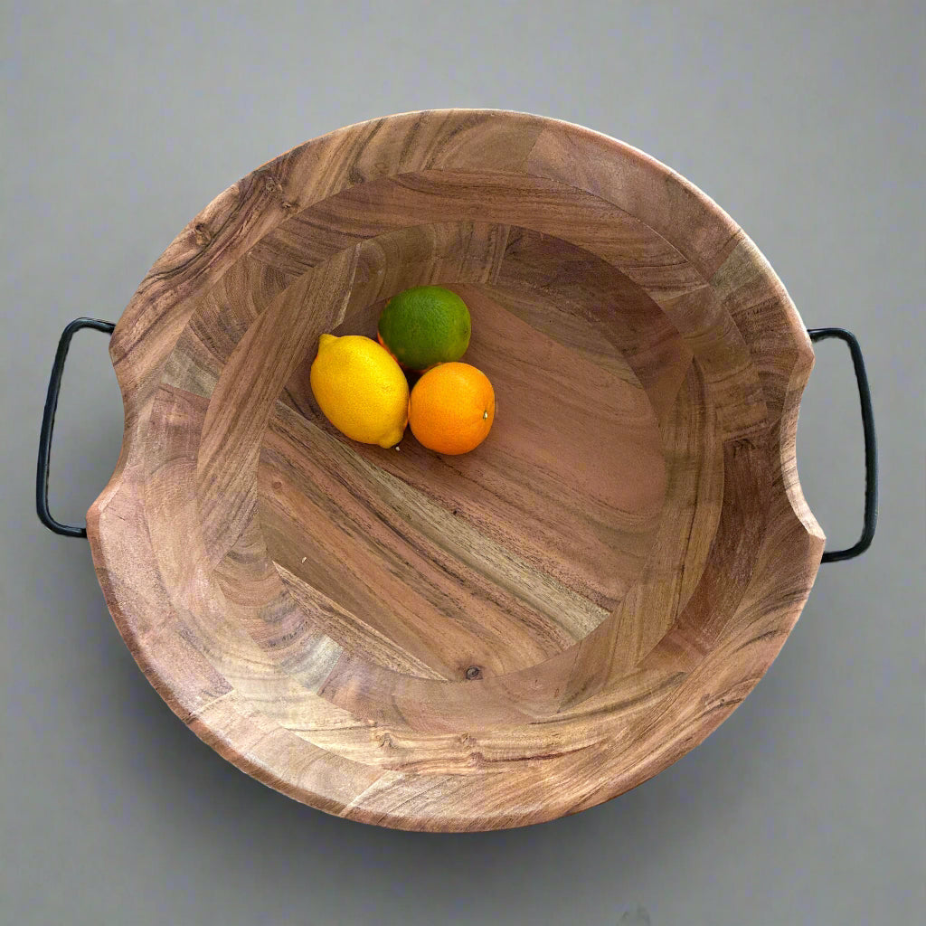 Wooden bowl with black handles containing lemons and a lime on a wooden surface.