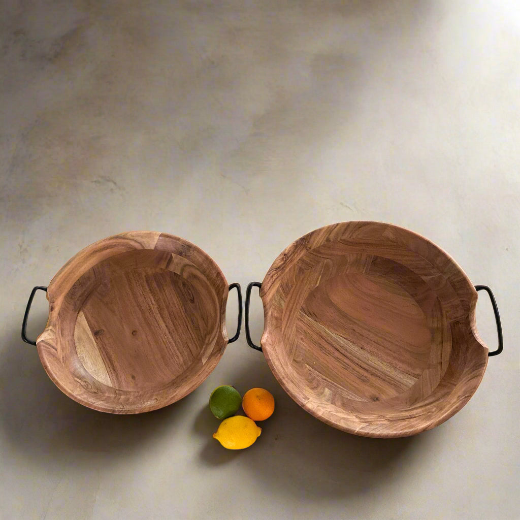 Two wooden bowls on a kitchen floor with fruits and a laptop.