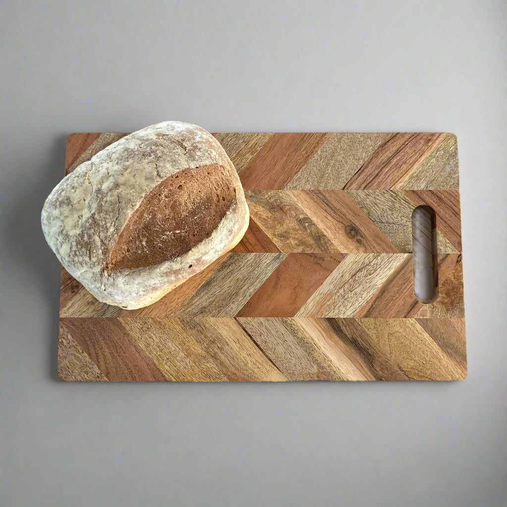 Wooden cutting board with a loaf of bread on a wooden surface