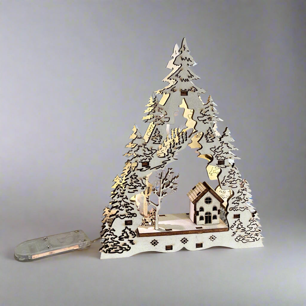 Decorative LED Christmas tree with houses and trees on a wooden base against a grey background