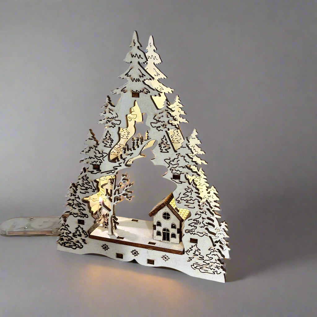 Decorative Christmas scene with trees and a house on a wooden surface