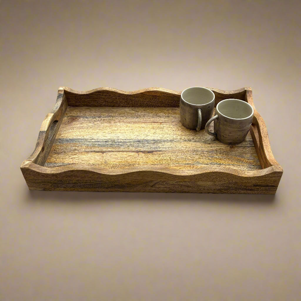 Wooden tray with two ceramic mugs on a wooden floor.