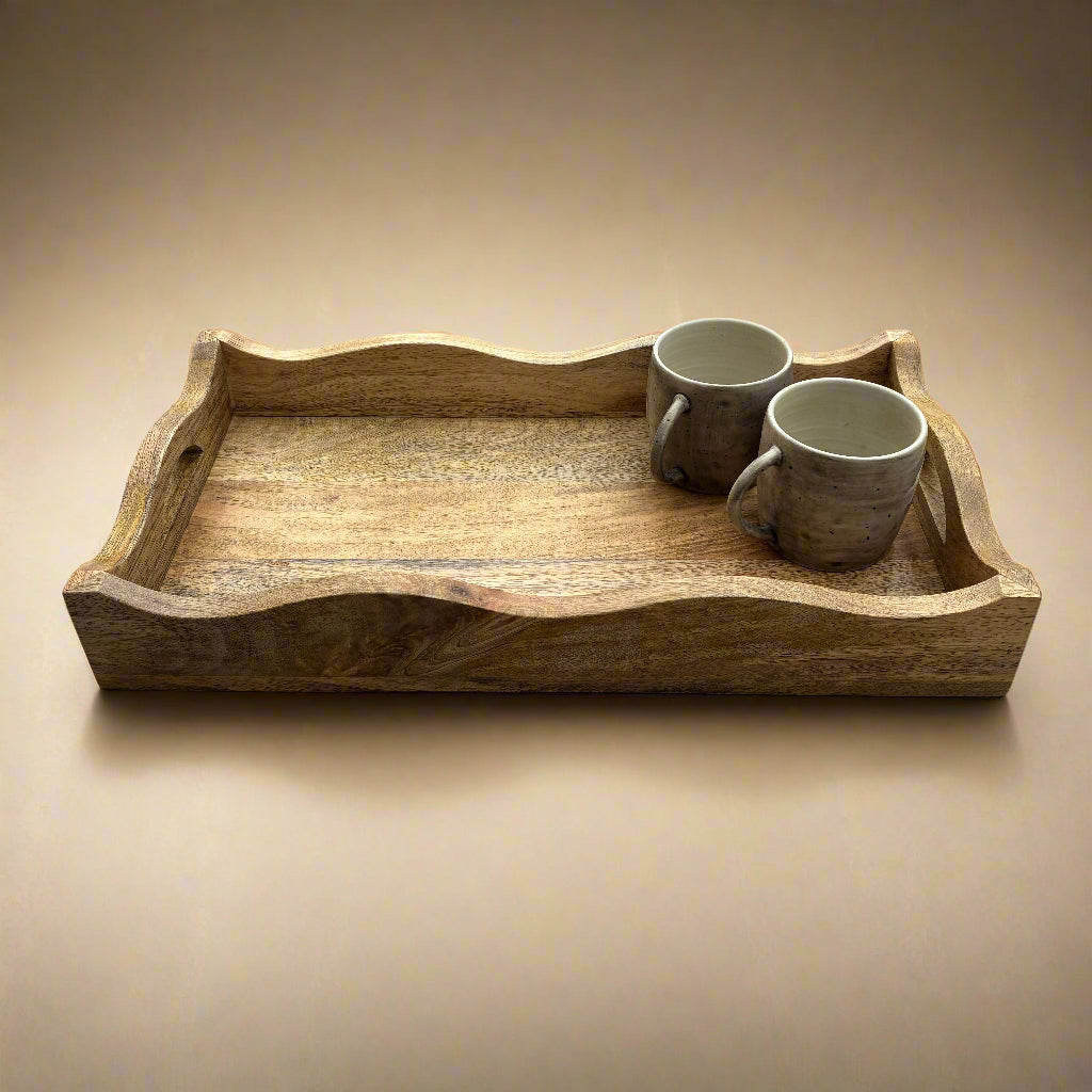 Wooden tray with two ceramic mugs on a wooden floor.