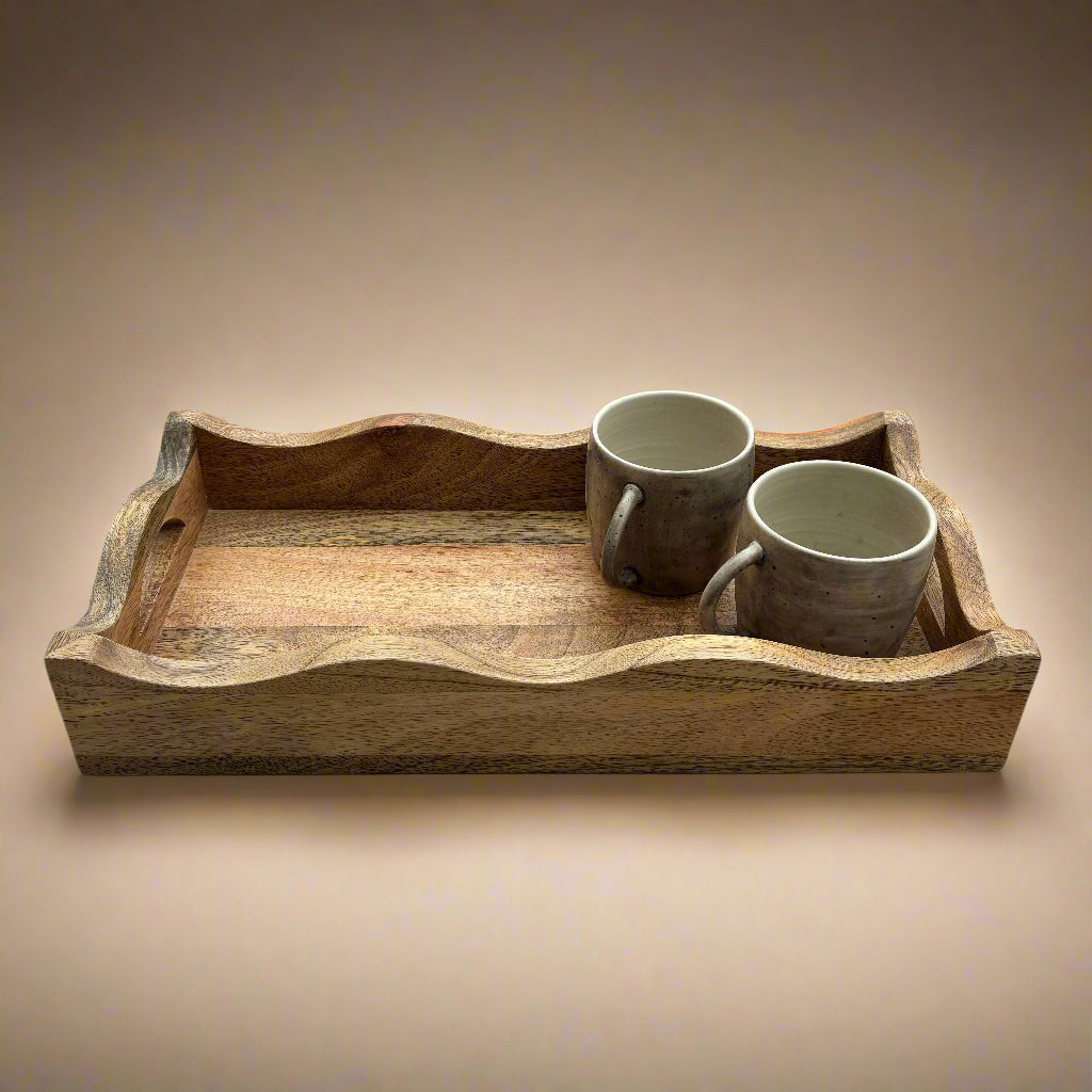 Wooden tray with two ceramic cups on a wooden floor.
