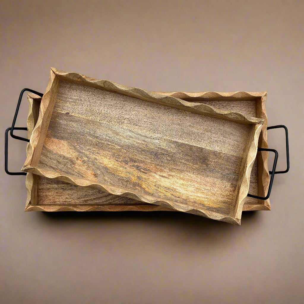 Wooden serving tray with black handles on a wooden floor