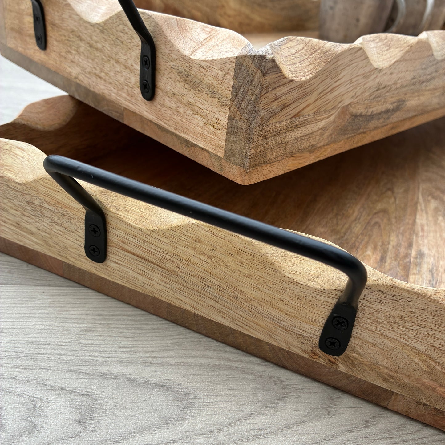 Wooden trays with black metal handles on a light gray surface