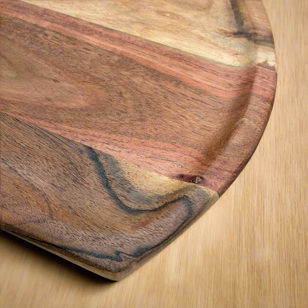 Wooden cutting board with a wavy grain pattern on a light gray surface