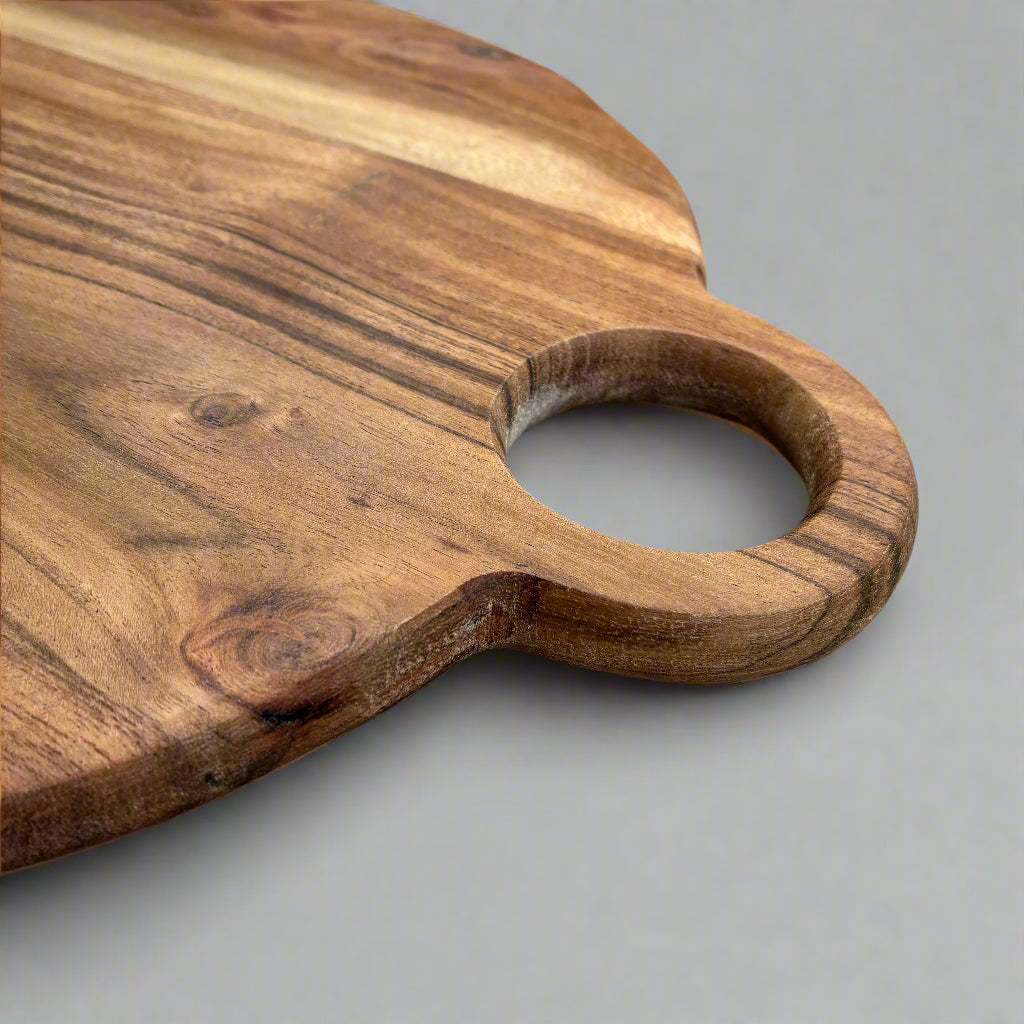 Wooden cutting board with handle on a wooden surface