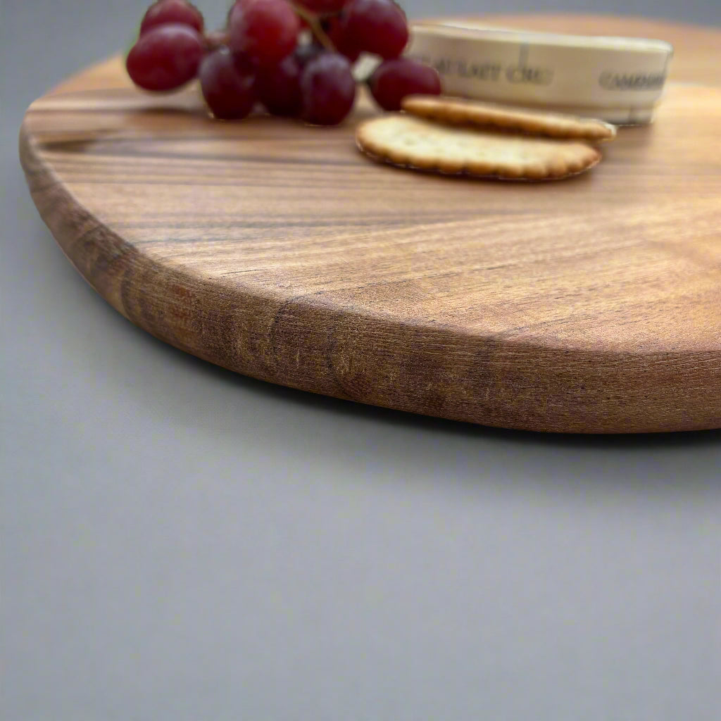 Wooden cutting board with grapes and crackers on a gray surface