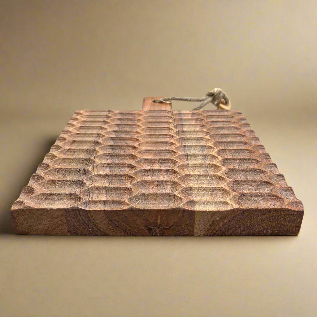 Wooden cutting board with a textured surface on a wooden floor.