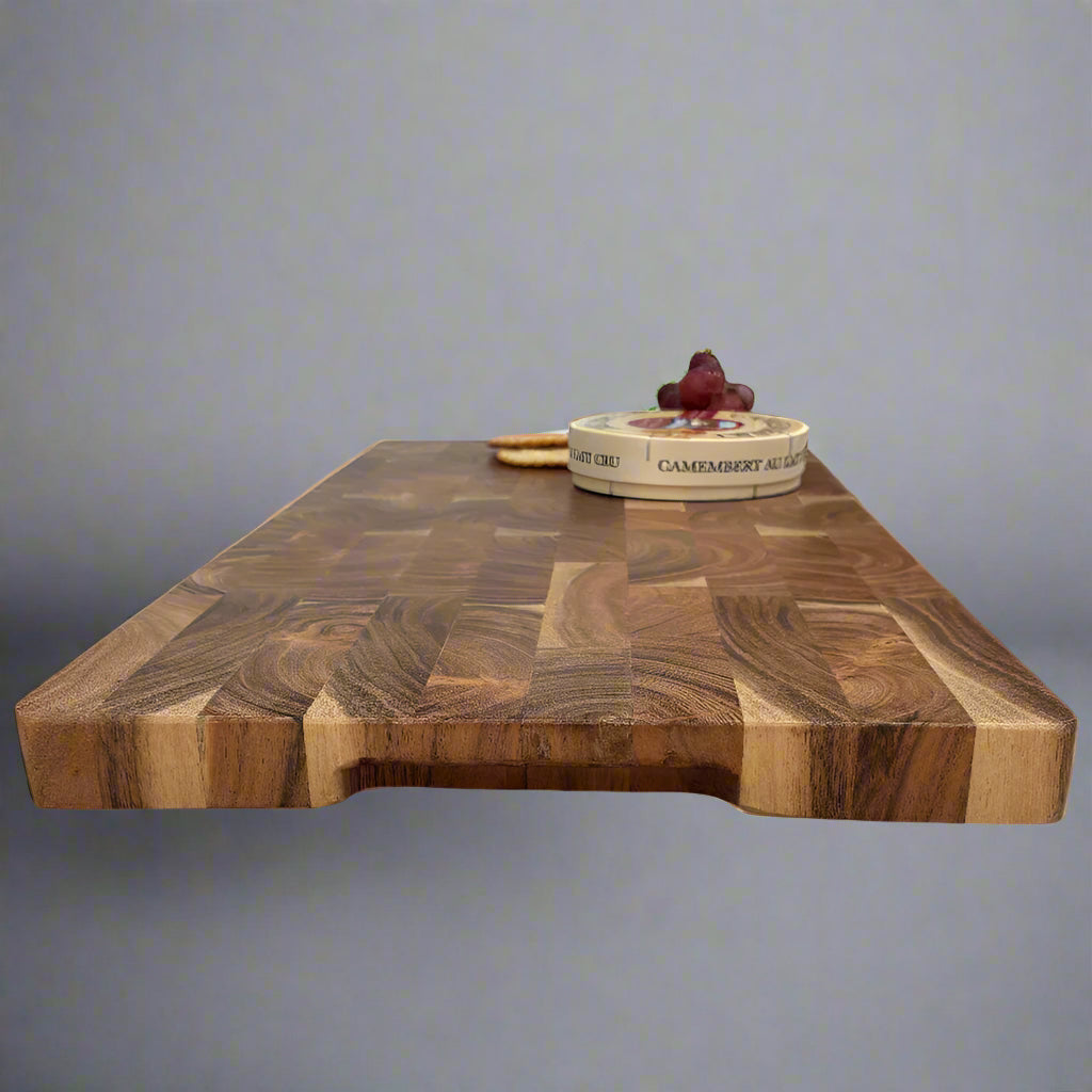 Wooden cutting board on a wooden floor with a radiator and wicker basket in the background.