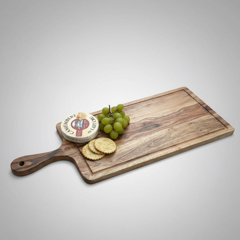 Wooden cutting board with cheese, crackers, and grapes on a wooden floor