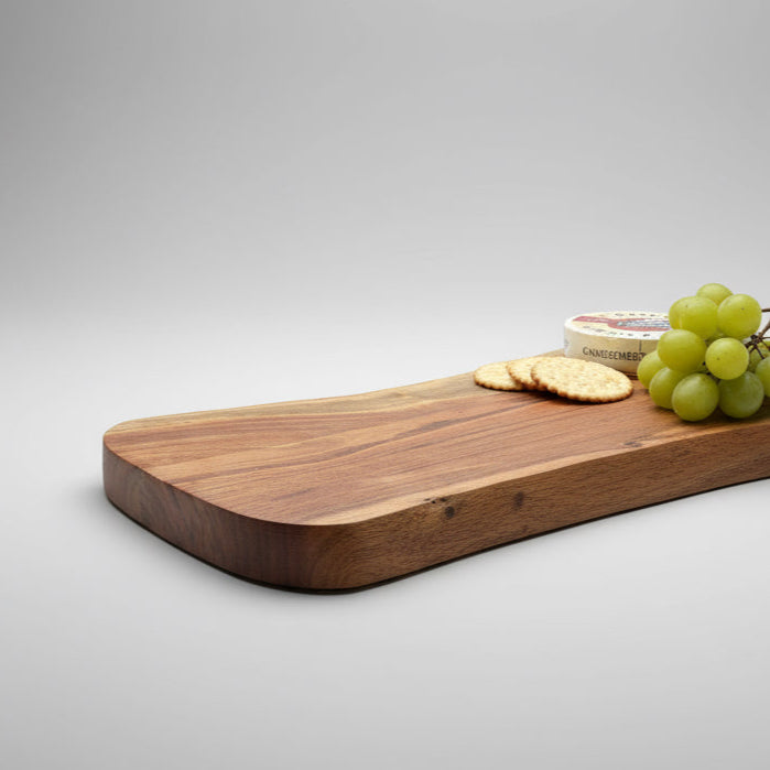 Wooden cutting board with grapes and crackers on a gray surface