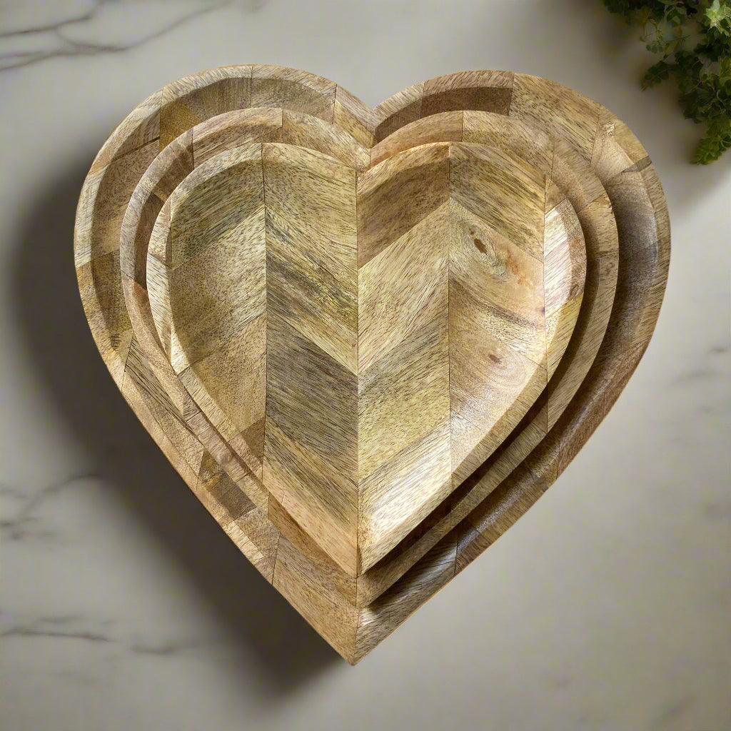 Set of three wooden heart-shaped trays on a marble surface