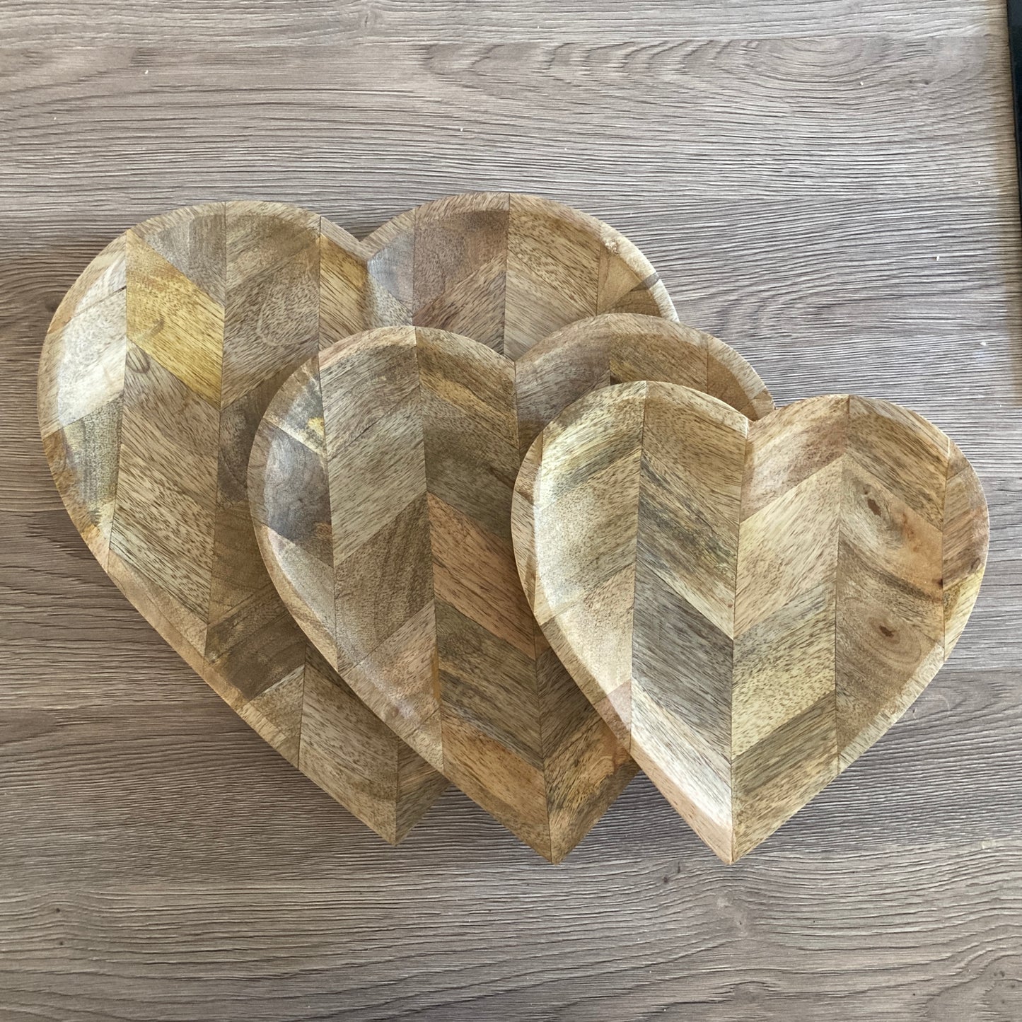 Set of three wooden heart-shaped bowls on a wooden surface