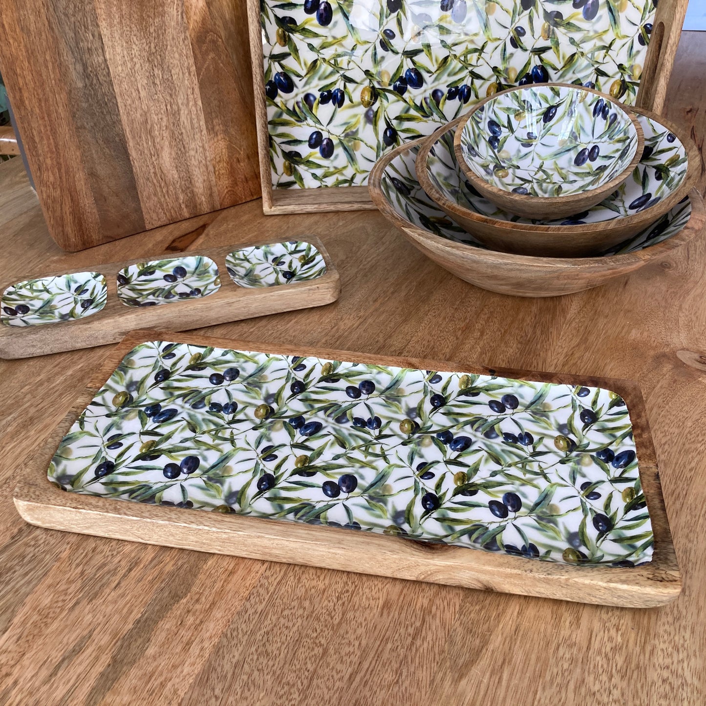 Wooden trays and bowls with olive pattern on a wooden surface