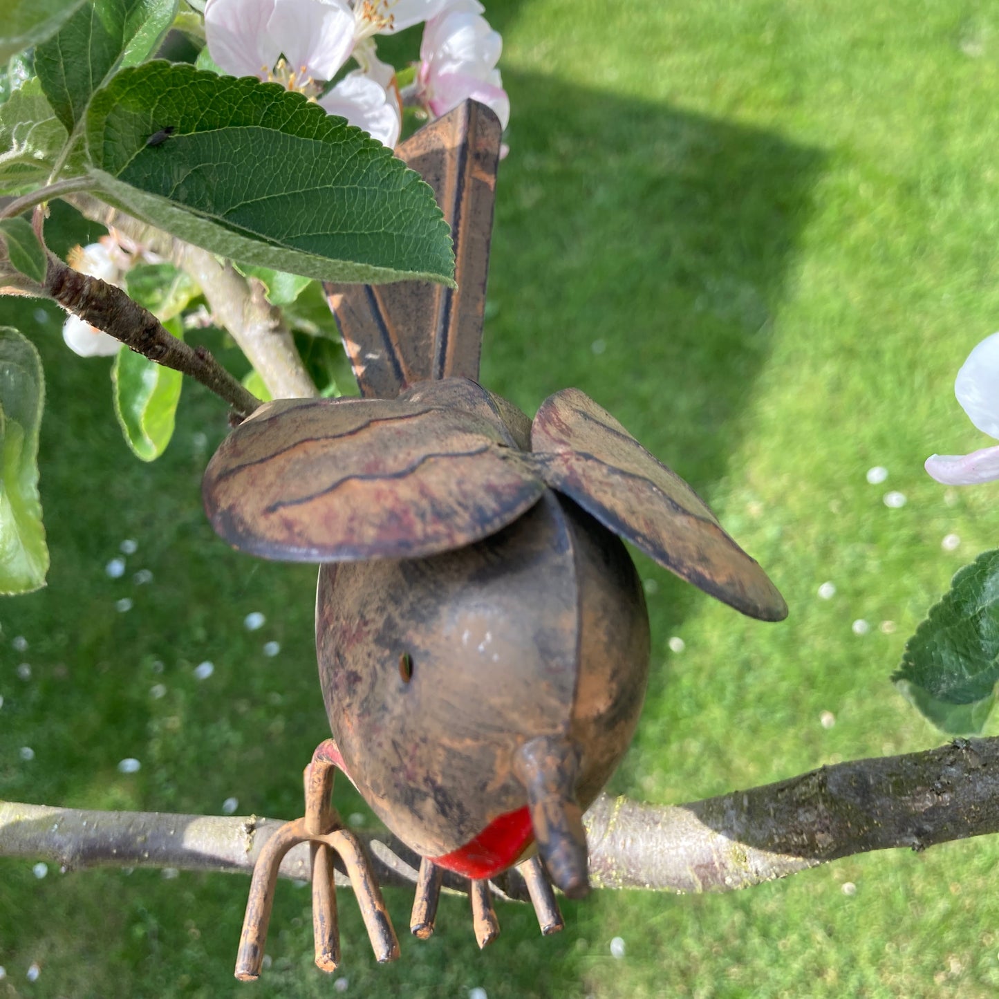 Tin robin garden ornament in tree from above.
