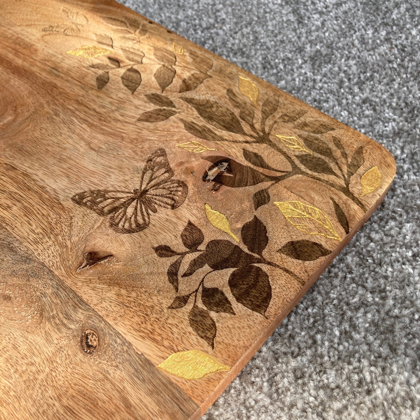 Floral design etched Mango wood food serving paddle board close up