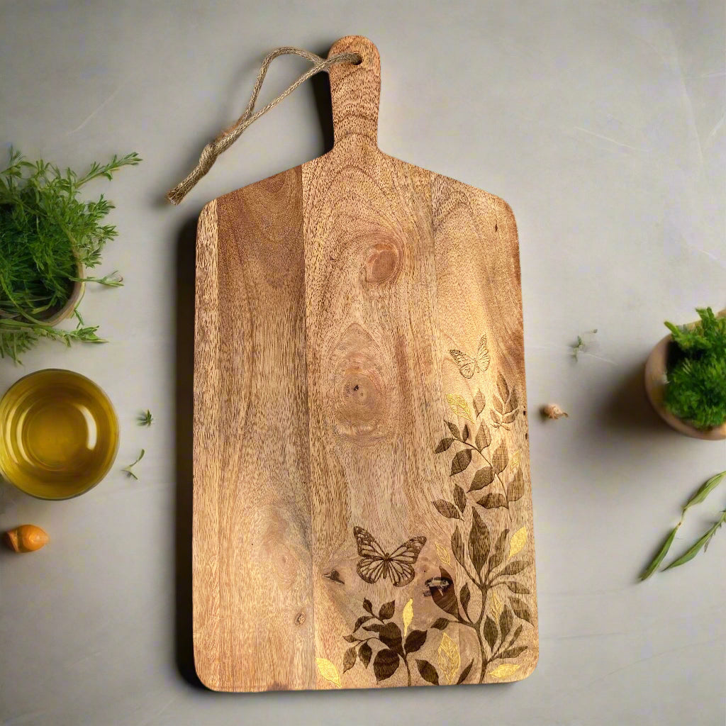 Floral design etched Mango wood food serving paddle board on a worktop