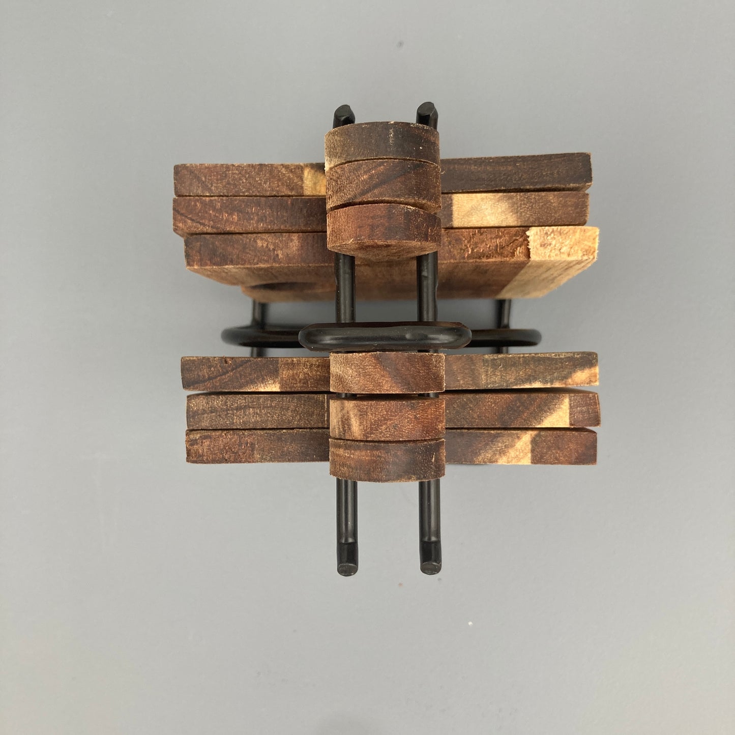 Set of 6 Acacia wood puzzle shaped coasters on a metal holder. View from above.