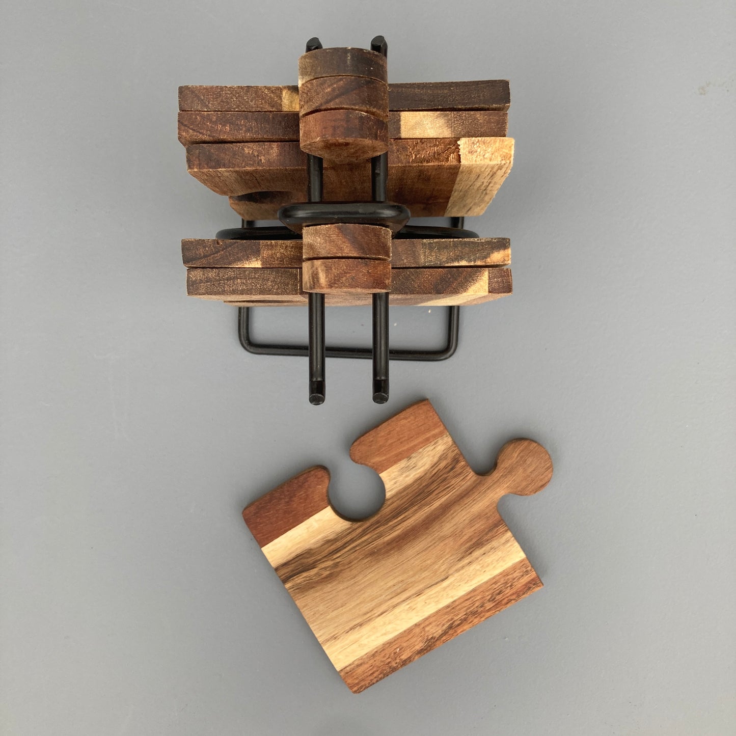 Set of 6 Acacia wood puzzle shaped coasters on a metal holder. View of coaster from above.