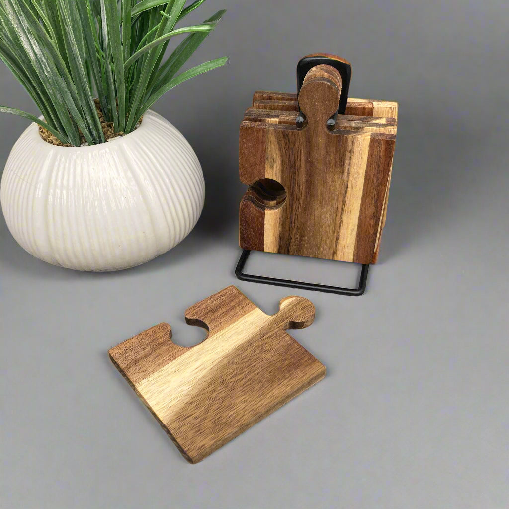 Set of 6 Acacia wood puzzle shaped coasters on a metal holder. One piece on table.