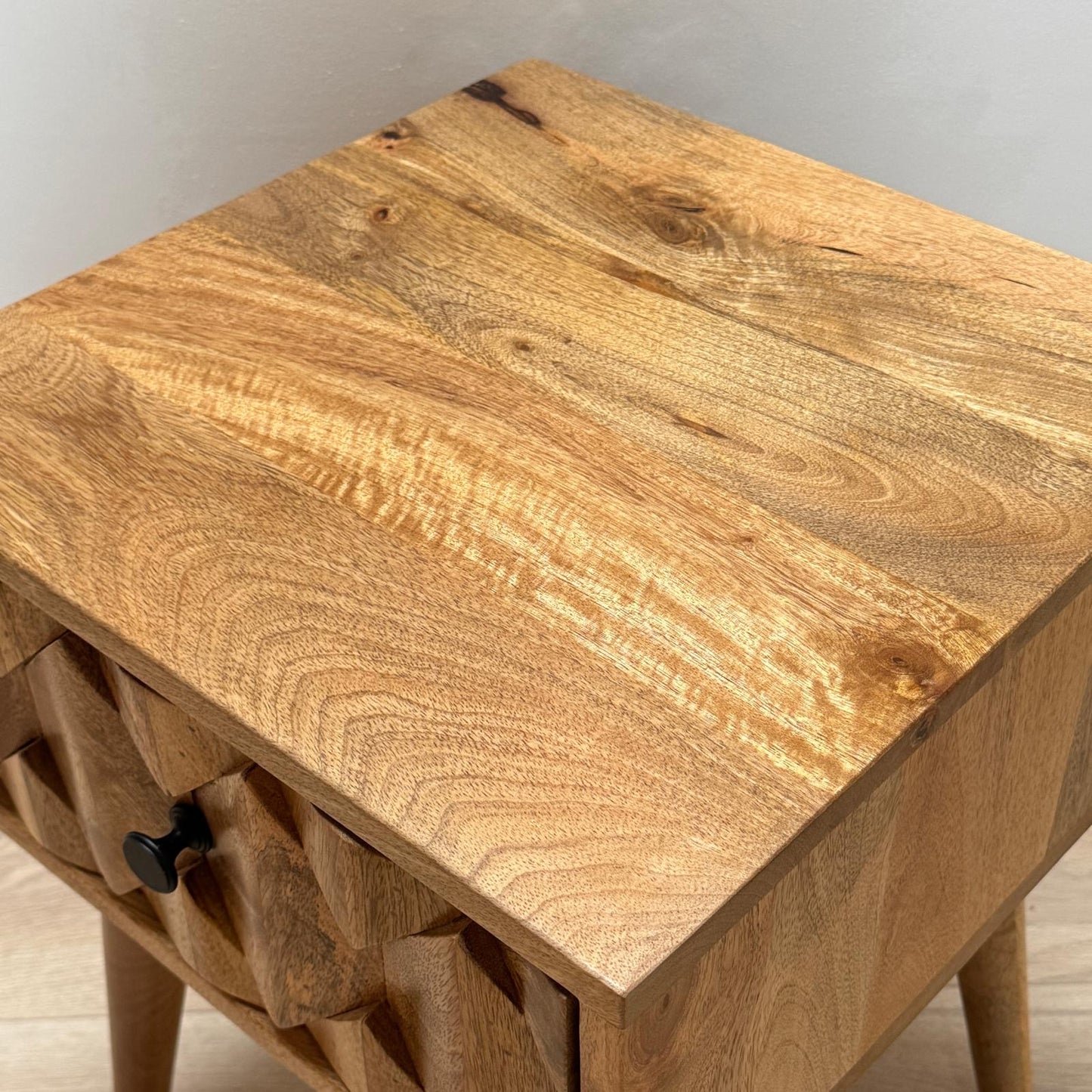 Wooden side table with a single drawer on a neutral background