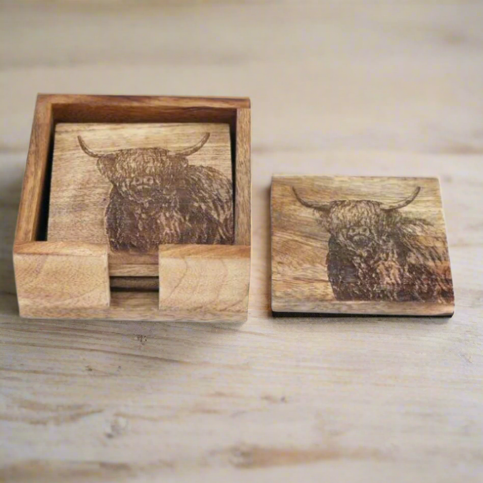 Set of 4 Mango wood square coasters with holder. 10cm square - Etched with Highland cow. One coaster on table.