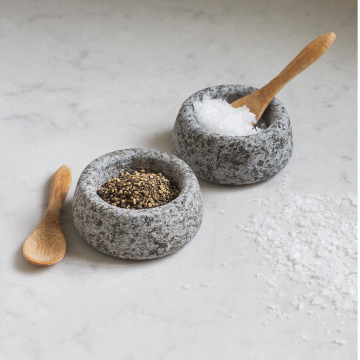 Two stone bowls with wooden spoons on a light surface