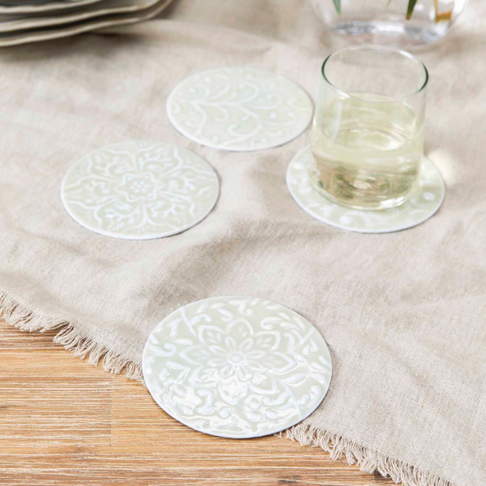 Set of 4 metal coasters on picnic blanket.