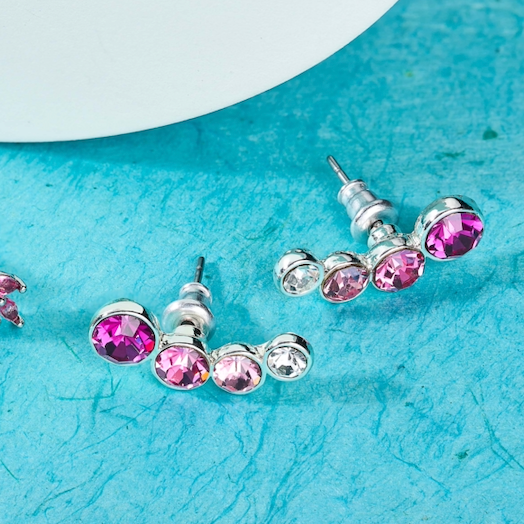 Rhodium pink crystal stud earrings on blue back ground.