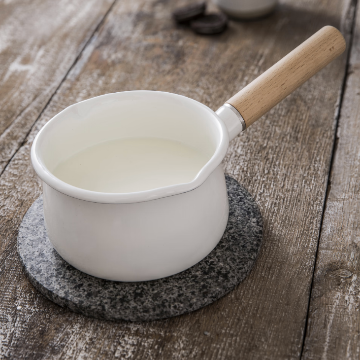White saucepan with wooden handle on a wooden surface