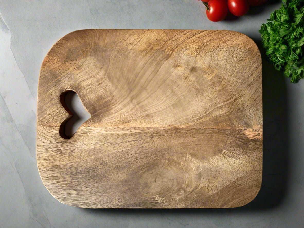 Mango wood chopping boards with cut out hearts. Single board on table.