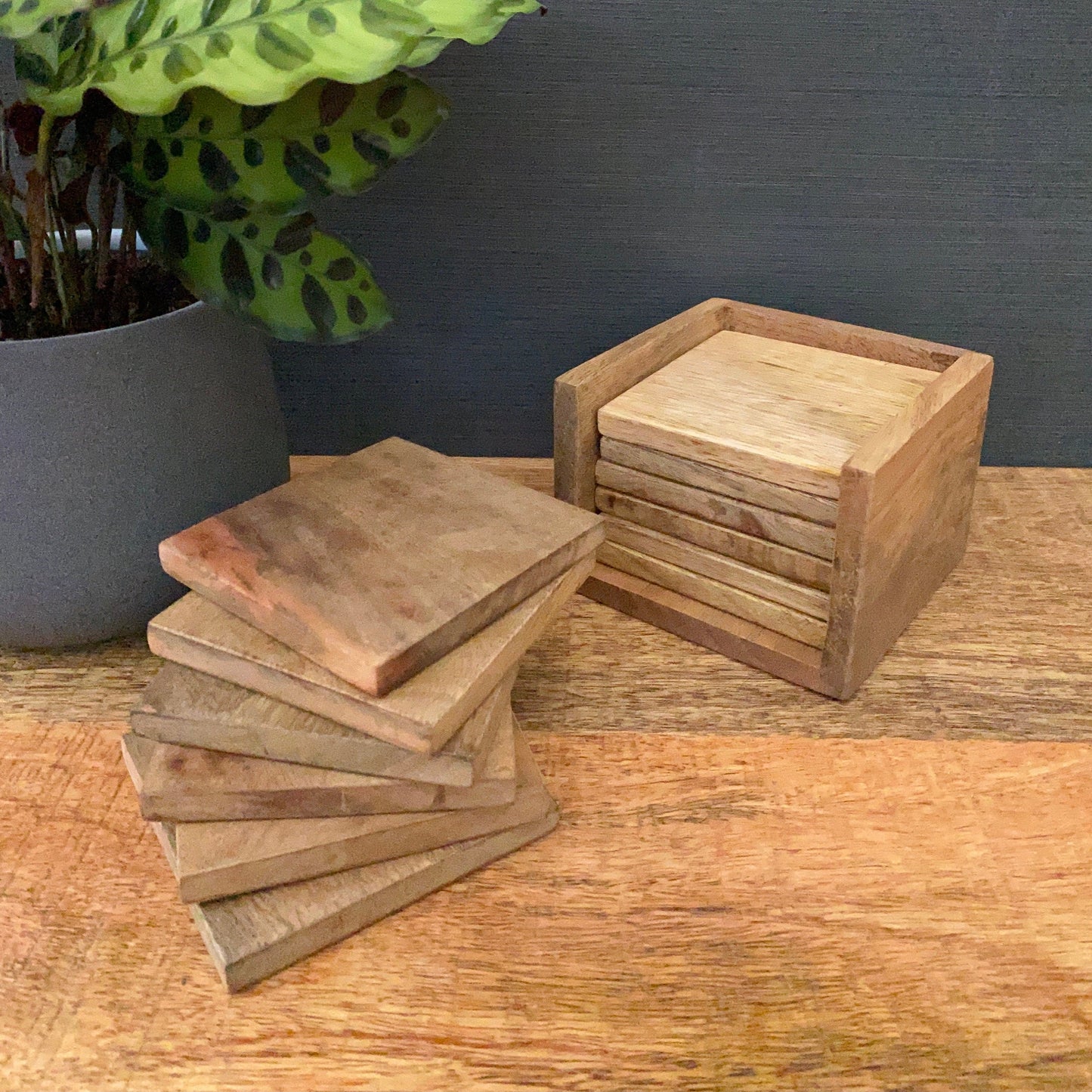 Set of 6 solid Mango wood square coasters with holder. Additional six coasters shown stacked next to holder.