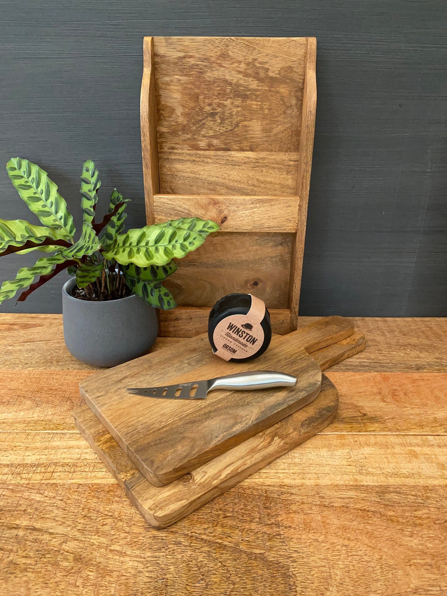 Set/2 Mango wood chopping boards with wall mountable holder. Shown with cheese and a knife.