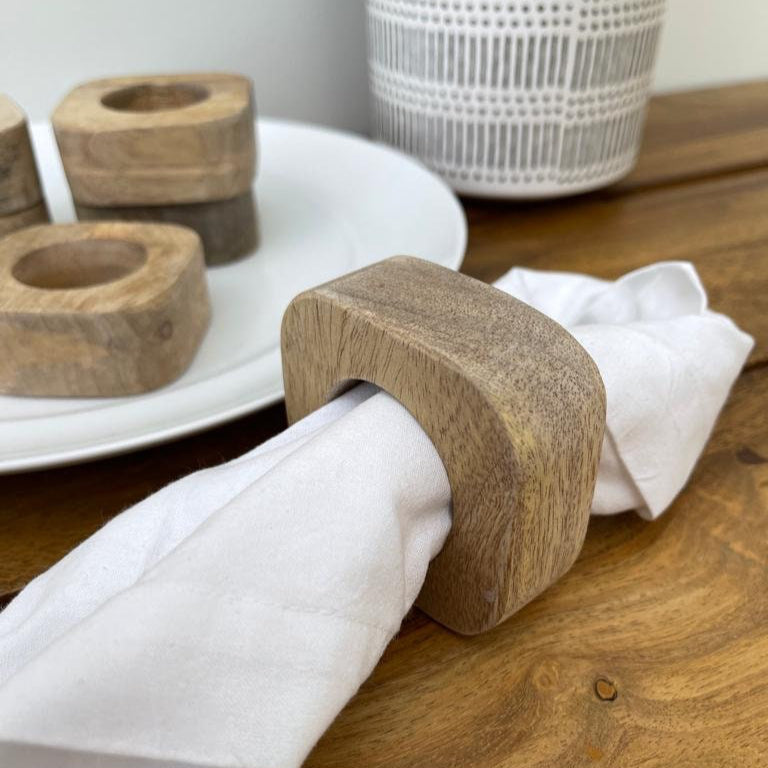 Set of solid Mango wood napkin rings. With napkin on table.