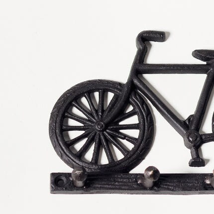 Black painted cast iron bike design set of hooks. Close up of wheel.