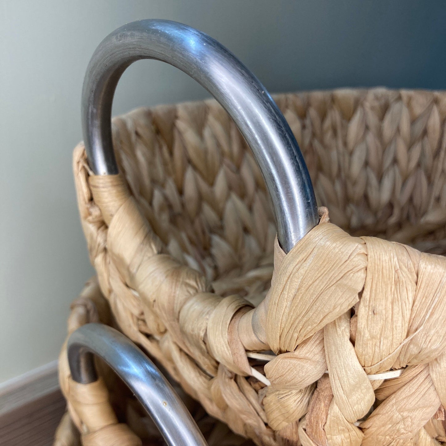 Woven water hyacinth fruit baskets with aluminium loop handles. Close up of handle.