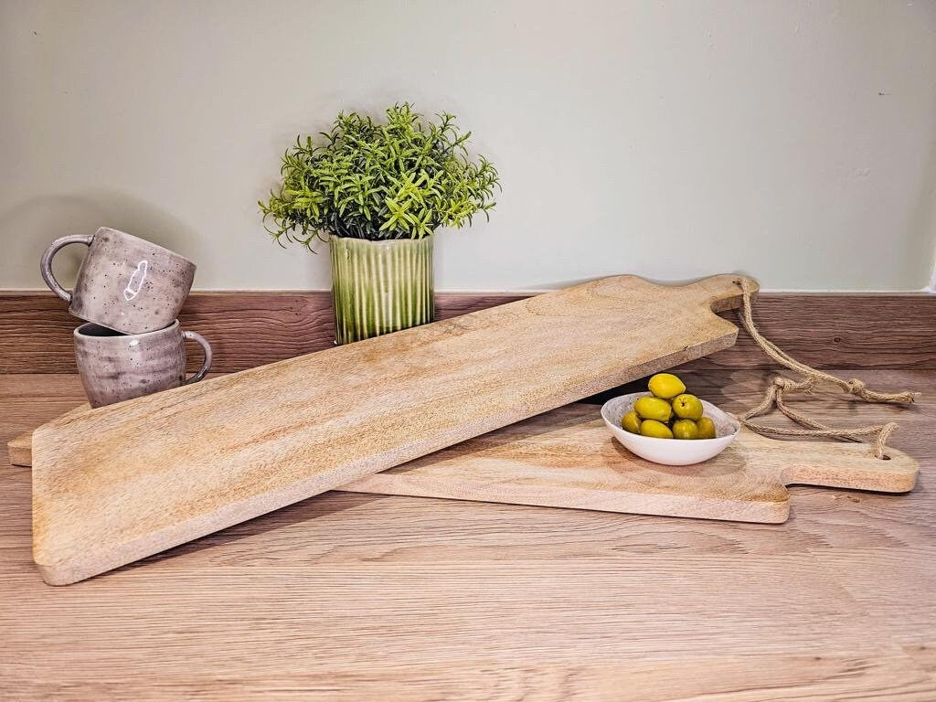 Long slim Mango wood paddle grazing boards on a worktop