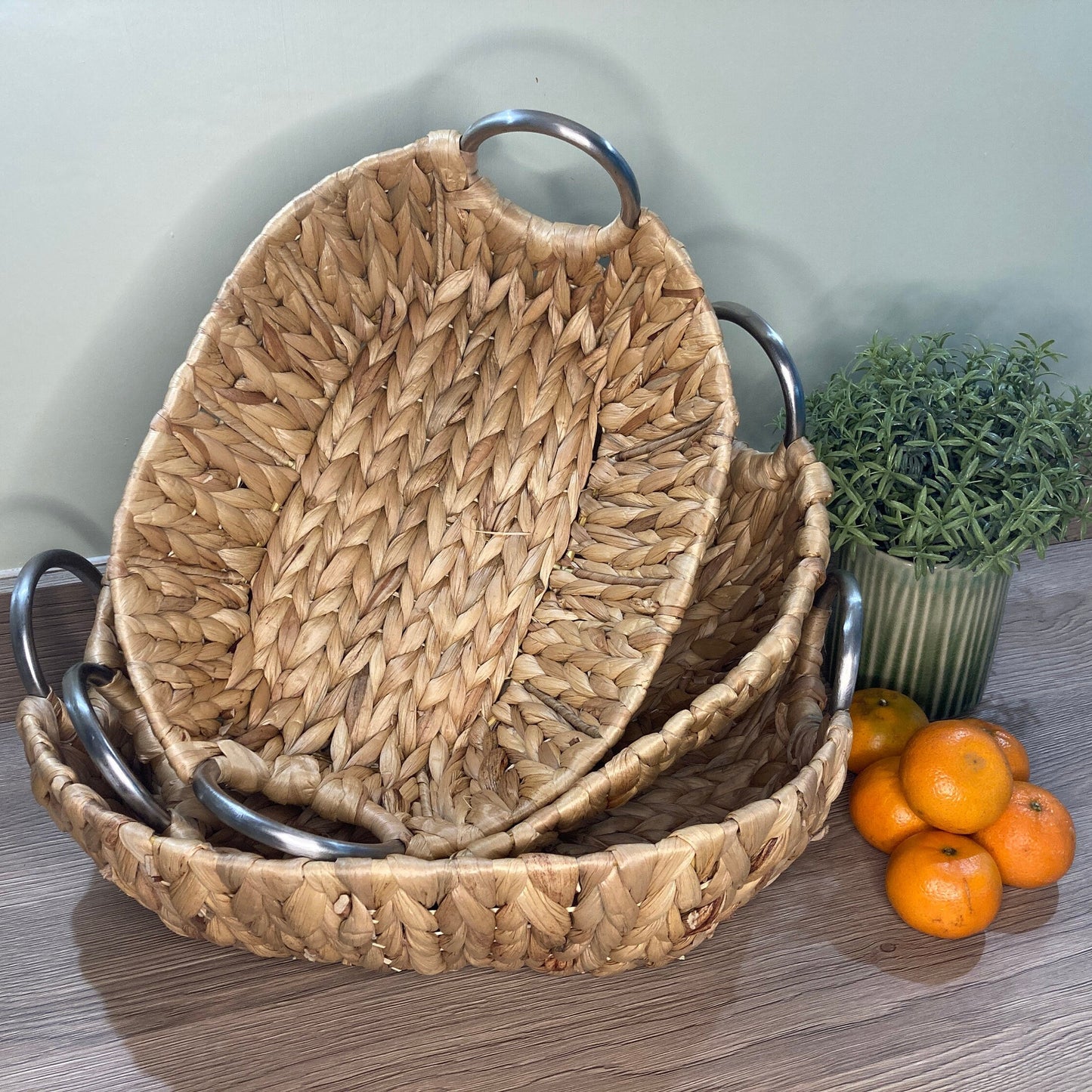 Woven water hyacinth fruit baskets with aluminium loop handles. 3 baskets stacked.