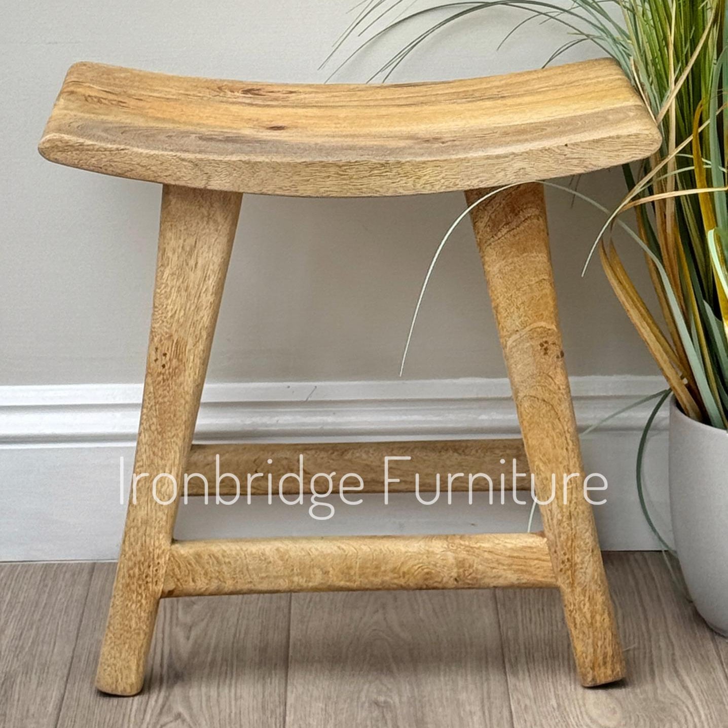 Curved rustic Mango wood stool single (light).